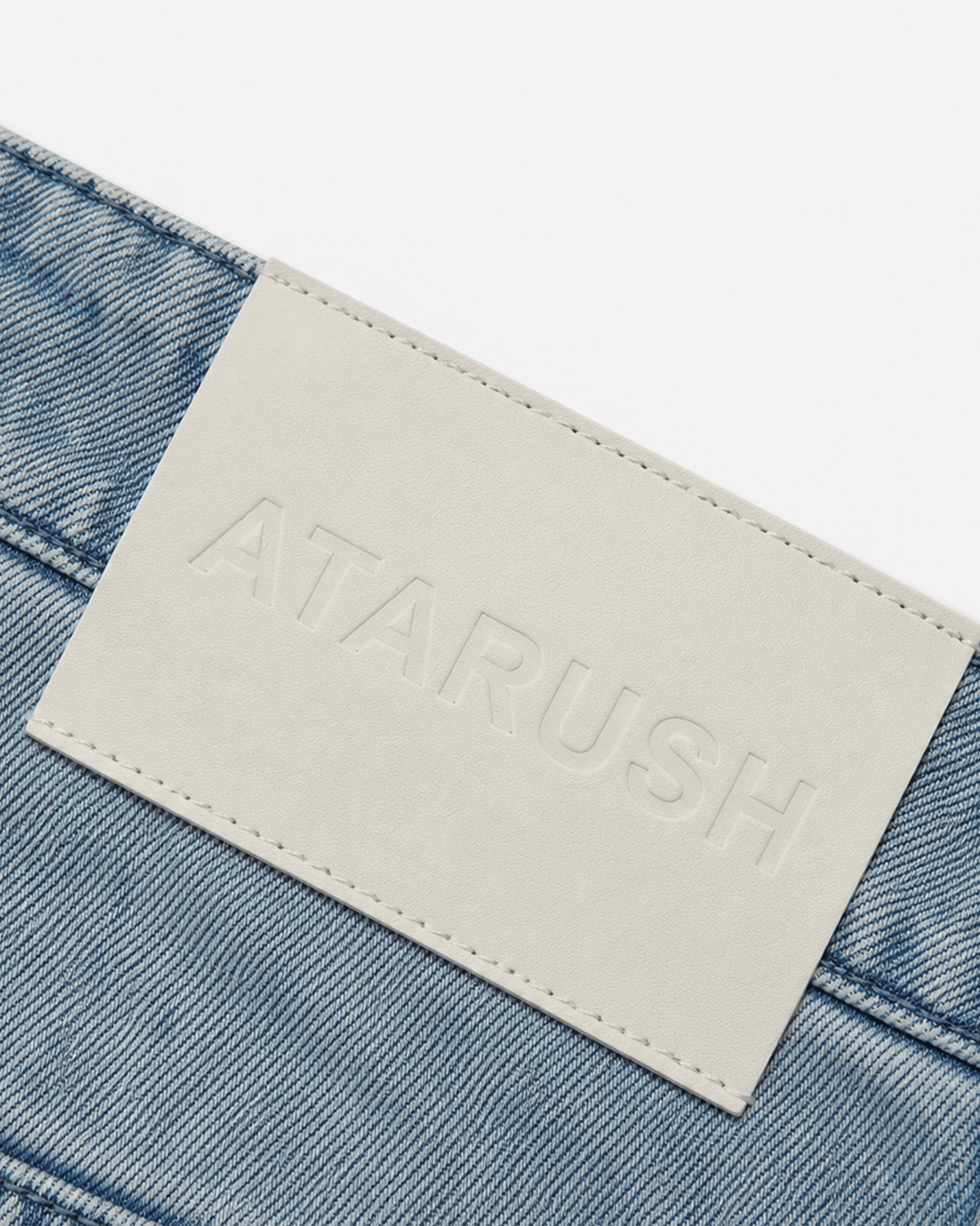 ATARUSH embossed leather patch detail on Rider denim shorts